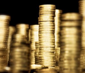 Tall stacks of UK pound coins against a dark background.